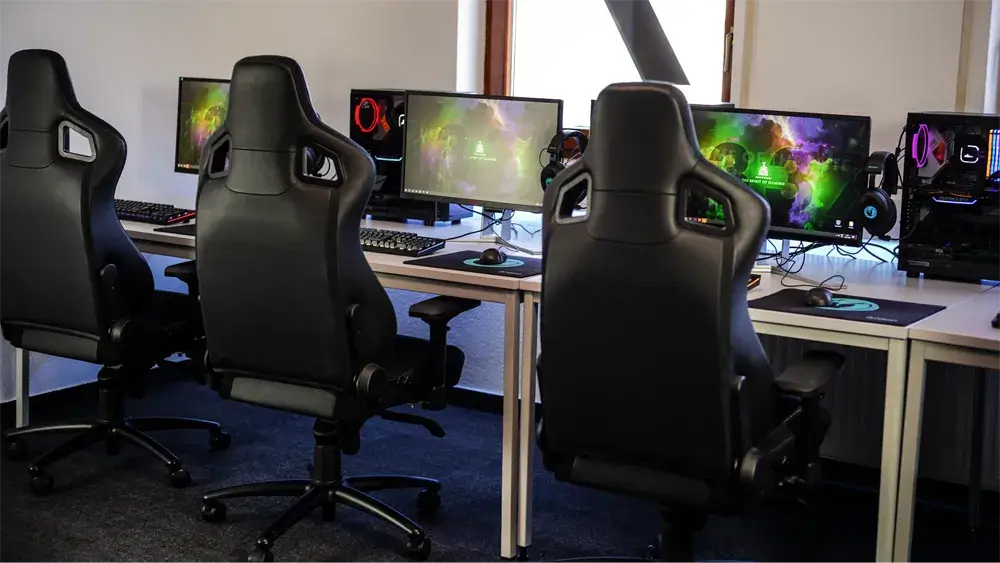 Three gaming chairs, desks, and monitors.